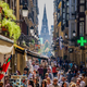 Crowded street full of people with the steeple of a church visible between buildings